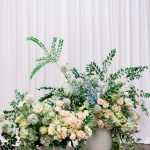 Floral decor for a wedding ceremony at 128 South, featuring two lush, elegant arrangements in urns flanking a draped backdrop.