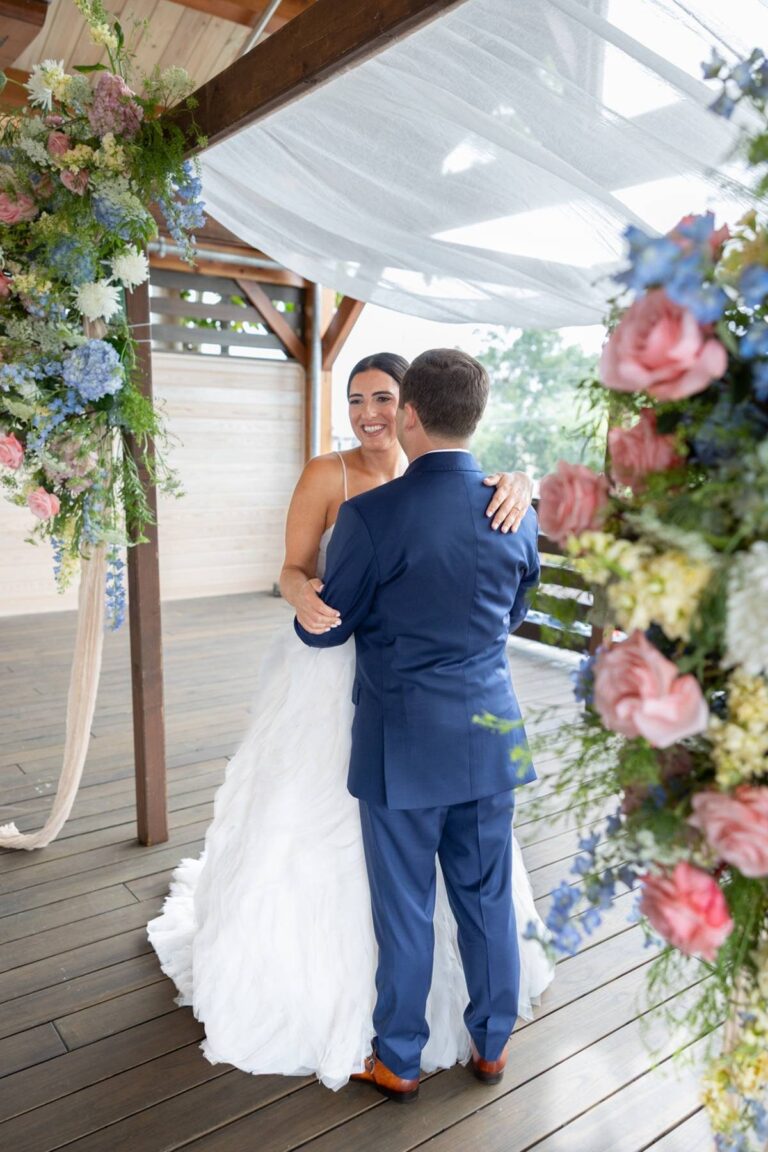 Couple embracing beside a floral arch on the 128 South rooftop