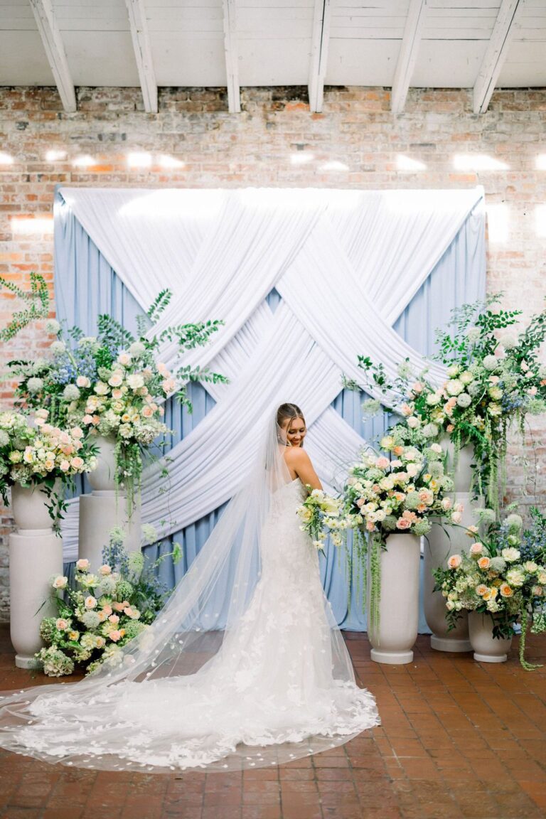 Bride in front of a draped floral backdrop at Bakery 105